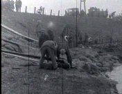 Bestand:Stoppen van een gat in de dijk met zakken, het (1926).jpg